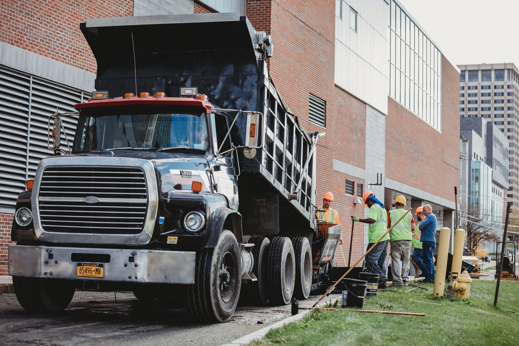 A tri-axle dump truck staged alongside an Industry Standard USA crew on a VA campus