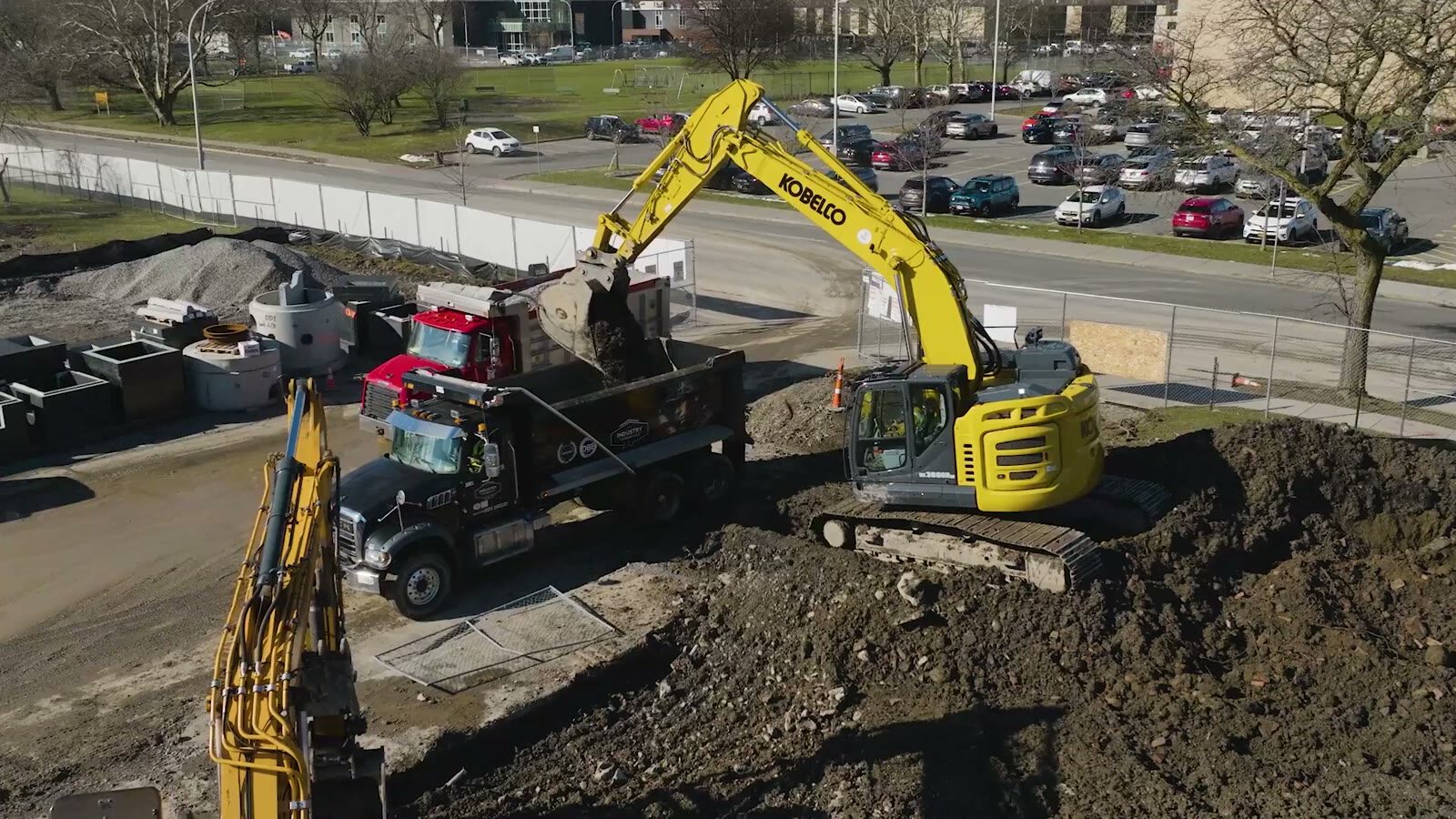 Aerial view of an Industry Standard USA crew loading a dump truck with an excavator on an active sitework project